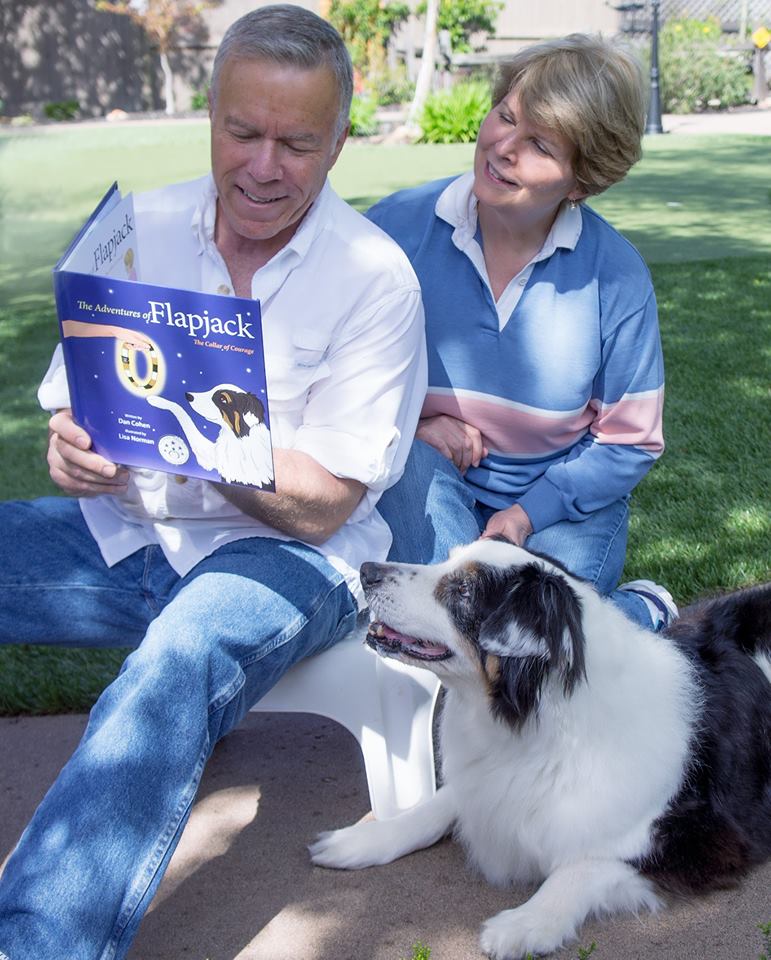 Flapjack, Dan and Kim sitting closely together outdoors as Dan reads aloud from The Adventures of Flapjack – The Collar of Courage.